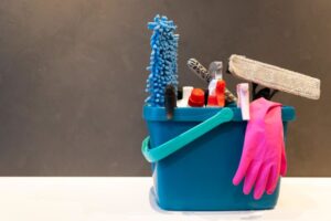 imagen de un cubo de limpieza con guantes, mopa y productos básicos de limpieza
