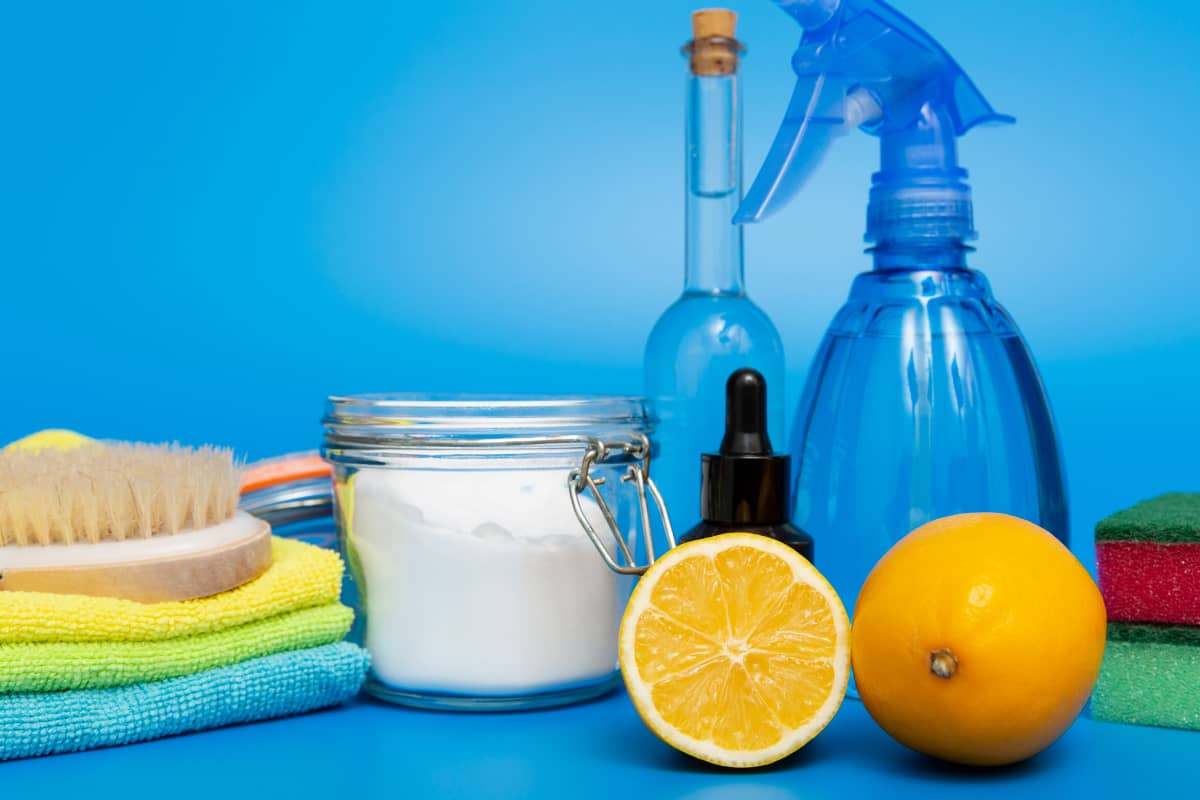 Productos de limpieza naturales junto a un bol de sal y dos rodajas de naranja