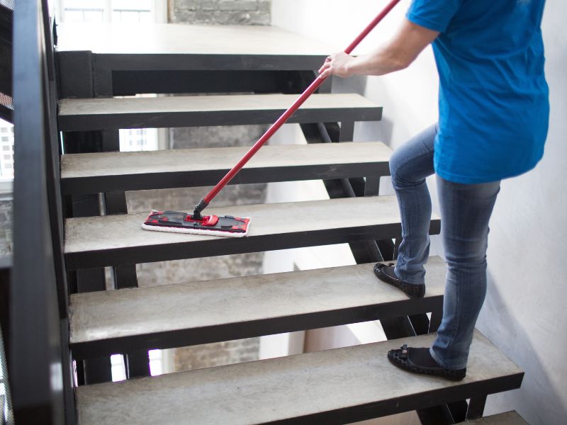 Limpieza de escaleras de una comunidad con mopa.
